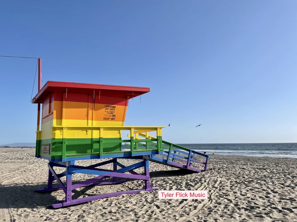 ‘Tyler Flick’ releases new single ‘Rainbow Lifeguard Tower’ about a real lifeguard tower painted rainbow on the beach.